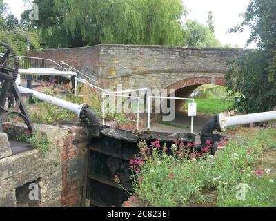 Vue sur l'une des portes d'écluse de Stoke Bruerne sur le Grand Union, où le pont routier traverse le canal. Banque D'Images