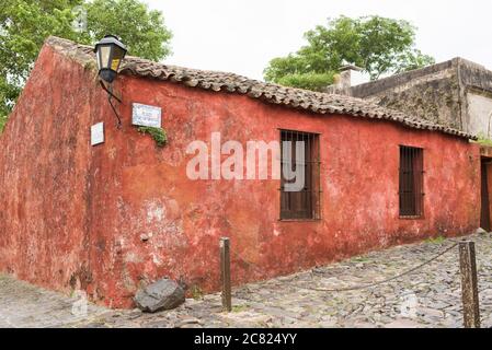 Coin de la rue San Pedro et de la rue de sours (Calle de los suspiros) dans le centre historique de Colonia del Sacramento, Uruguay. Maison rouge et Banque D'Images