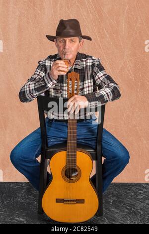 Vieil homme attrayant avec des yeux clairs et style rural boire la perfusion typique en Argentine et en Uruguay appelé Mate Banque D'Images