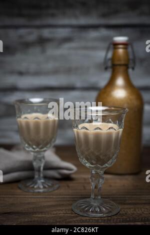 Photo verticale de deux vieux verres avec liqueur douce à la main sur fond rustique Banque D'Images