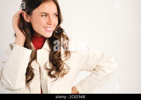 Magnifique charmante fille qui regarde de côté sur fond blanc Banque D'Images