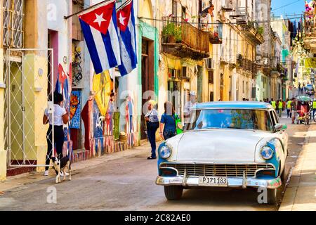 Scène urbaine avec drapeaux cubains, voiture classique et des bâtiments en décomposition colorés dans la vieille Havane Banque D'Images