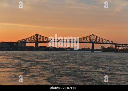 Vue sur la ville un pont en acier traversant une rivière au coucher du soleil. Pont Jacques Cartier, de l'autre côté de la rivière Saint-Laurent, Montréal, Québec, Canada Banque D'Images