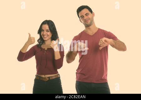 Studio shot of young woman smiling with woman giving Thumbs up et man giving Thumbs down Banque D'Images