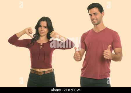 Studio shot of young woman smiling with up and woman giving Thumbs down Banque D'Images