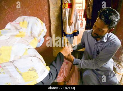 Un travailleur de la santé administre des gouttes de vaccin contre la polio à un enfant lors de la campagne de vaccination contre la polio qui a lieu dans la région de Nazimabad à Karachi le lundi 20 juillet 2020. Une petite campagne de vaccination contre la polio sera lancée dans la métropole à partir d'aujourd'hui, à Baldia, Orangi Town, North Nazimabad, Liaquatabad et dans la région OÙ environ 260,000 enfants âgés de moins de cinq ans seront administrés le vaccin oral contre la polio. Banque D'Images