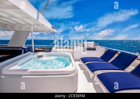 Terrasse arrière ensoleillée d'un grand yacht privé de luxe avec bain à remous, chaises longues et barbecue. Vivre la bonne vie. Banque D'Images