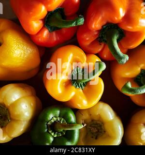 Poivrons jaunes, verts et oranges en démonstration de légumes frais, en vente sur un marché agricole ou agricole. Banque D'Images