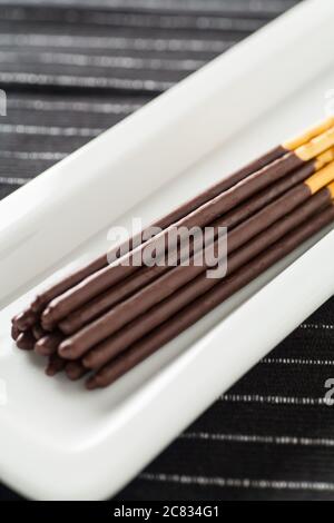 Image verticale des bâtonnets de chocolat Pocky sur un longue plaque blanche Banque D'Images