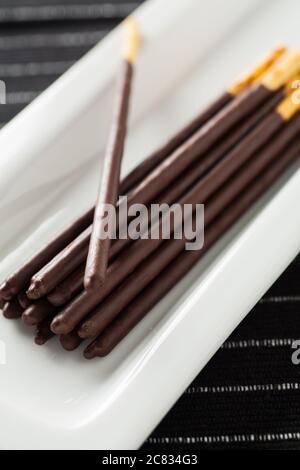 L'image verticale des bâtonnets de chocolat pocky repose sur un long plaque blanche Banque D'Images