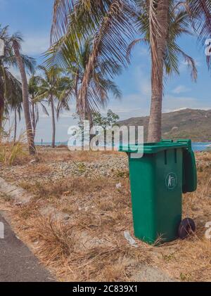 Ouvert grand vide poubelle en plastique vert vide dans un village moderne et confortable près de la mer et des palmiers. Contrôle infectieux, élimination des déchets, élimination Banque D'Images