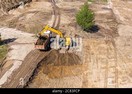 pelle rétro et camion à benne basculante sur chantier. machines industrielles effectuant des travaux de terrassement. photographie aérienne Banque D'Images