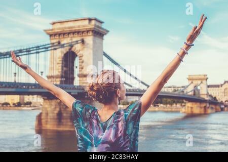 Heureusement, une jeune femme à tête rouge a soulevé des bras à Chain Bridge, Budapest, Hongrie Banque D'Images