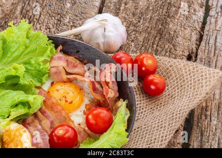 Plat d'œufs frits avec bacon, tomates fraîches, salades, roquette. Petit déjeuner Banque D'Images