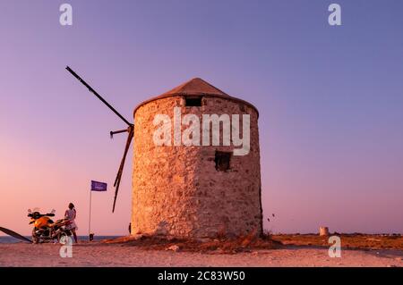 Lefkada, Grèce. 18 août 2011. Motocyclistes regardant la mer et le coucher du soleil à la plage de Milos, à côté du vieux moulin. Banque D'Images
