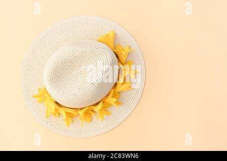 Chapeau de paille avec fleurs de nénuphars jaunes sur fond pastel. Modèle rétro élégant. Fond jaune. Concept de mode d'été. Copier l'espace. FL Banque D'Images