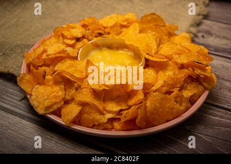 Croustilles sur un plateau rond et une casserole avec sauce au fromage. Gros plan Banque D'Images