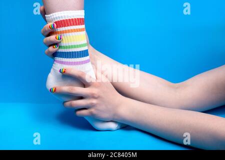 Photo des mains tenant la jambe en chaussettes aux couleurs arc-en-ciel Banque D'Images