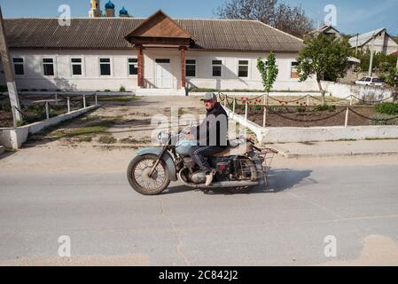 Trebujeni / Moldova - 15 mai 2020: Homme moldave à moto devant le bâtiment en zone rurale Banque D'Images