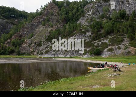 Groupe de personnes se détendre sur la rive pendant le rafting en canoë sur la rivière. Les touristes radeau ou flottant sur la rivière de montagne. Banque D'Images