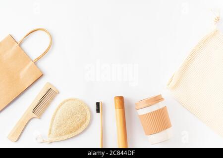 Placez les articles réutilisables sur une surface blanche. Brosse à dents en bambou, brosse à cheveux en bois, sac kraft en papier, sac en filet d'épicerie, tasse à café. Banque D'Images
