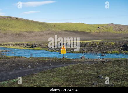 Islande, South Highlands, 1er août 2019 : traversée de la rivière du glacier bleu sur la route de montagne F210 avec avertissement le passage du texte nécessite un signe d'avertissement Banque D'Images