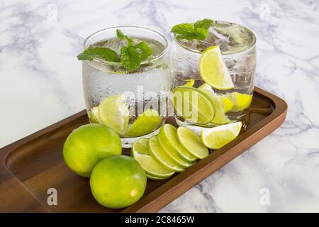 Boisson froide de citron coupée en morceaux dans le verre d'eau sur la tasse de bois Banque D'Images