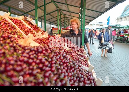 Riga / Lettonie - 18 juin 2020 : femme vendant des cerises sur le marché des capitaux Banque D'Images