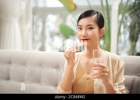 Malade femme mangeant des pilules avec un verre d'eau dans la main. Banque D'Images