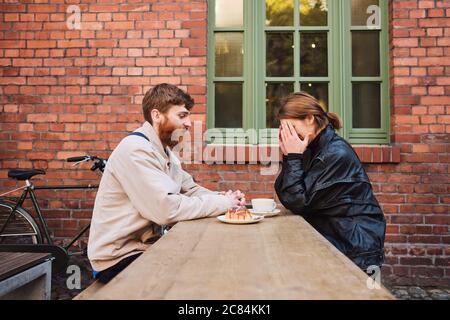 Vue latérale d'un jeune couple qui se coulait volontiers au café tout en se reposant ensemble dans le café de la rue Banque D'Images