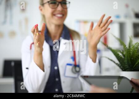 Une femme médecin en lunettes sourit et tient le stylo dans ses mains Banque D'Images