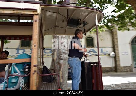 Sintra, Portugal - 12 juin 2017 : le chauffeur de tramway dans le cockpit d'un tramway rouge vintage, dans une rue en conduisant à Sintra. Panoramique pour capturer des images Banque D'Images