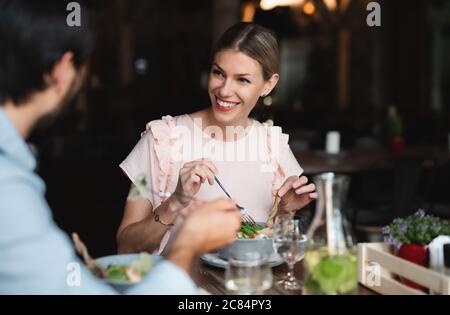 Couple heureux assis à l'intérieur dans le restaurant, manger. Banque D'Images