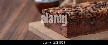 Gâteau éponge traditionnel taïwanais au goût de chocolat (taïwanais castella kasutera) sur une table de fond en plateau de bois avec les ingrédients, gros plan. Banque D'Images