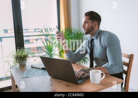 Jeune bussinessman travaillant et buvant du café à son bureau Banque D'Images