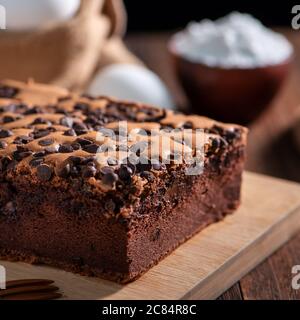 Gâteau éponge traditionnel taïwanais au goût de chocolat (taïwanais castella kasutera) sur une table de fond en plateau de bois avec les ingrédients, gros plan. Banque D'Images