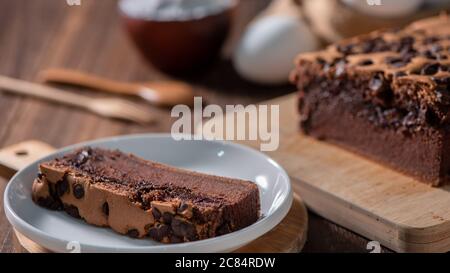 Gâteau éponge traditionnel taïwanais au goût de chocolat (taïwanais castella kasutera) sur une table de fond en plateau de bois avec les ingrédients, gros plan. Banque D'Images