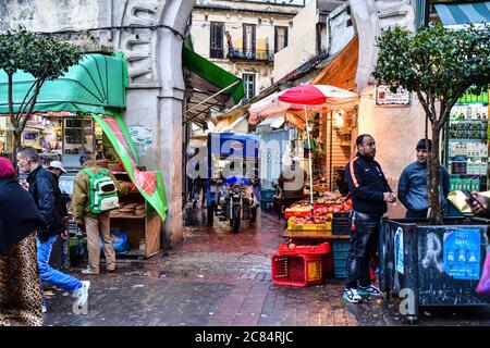 Maroc, Tanger: Scène de la vie quotidienne dans la médina. Marchands derrière leur stand, clients et livreur avec un tricycle de livraison Banque D'Images