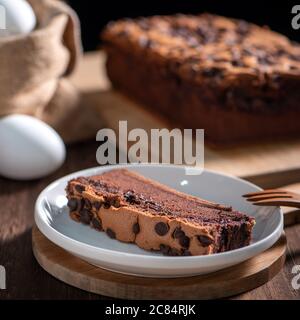 Gâteau éponge traditionnel taïwanais au goût de chocolat (taïwanais castella kasutera) sur une table de fond en plateau de bois avec les ingrédients, gros plan. Banque D'Images