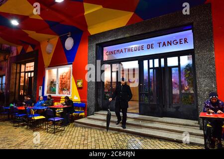 Maroc, Tanger: Scène de la vie quotidienne, la nuit, dans la médina. Homme en costume avec un parapluie noir sortant de la bibliothèque de films créée en 20 Banque D'Images