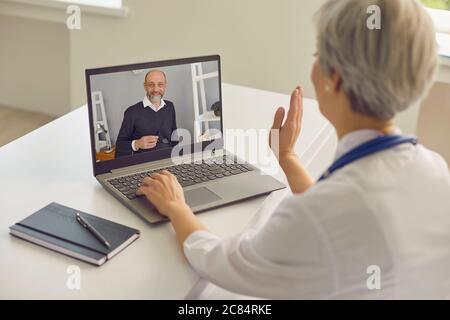 Médecin en ligne. Femme médecin ayant une consultation en ligne avec un patient senior à la clinique. Banque D'Images