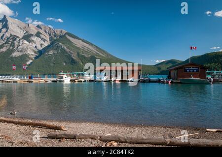 Drapeau canadien de la feuille d'érable et bateaux à moteur sur le lac Minnewanka, Banff, Alberta, Canada. Banque D'Images