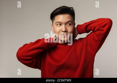 Image d'un homme asiatique charmant posant et regardant de côté isolé sur fond gris Banque D'Images