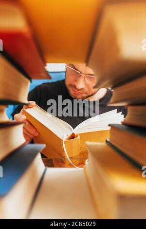 Cadre d'une pile de livres - à l'intérieur d'un homme de lecture d'âge moyen avec des lunettes - lire la littérature Banque D'Images