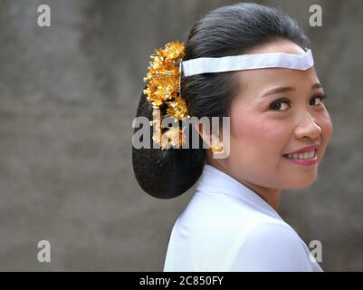 La jeune femme indonésienne balinaise porte une tenue blanche et sourit pour la caméra lors d'une cérémonie religieuse du temple hindou (festival Odalan). Banque D'Images