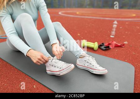 Chaussures de course femme coureur nouant la dentelle de la chaussure pour la course. Bonne fille souriante se prépare à courir laçage chaussures lacets. Coureur sportif Banque D'Images