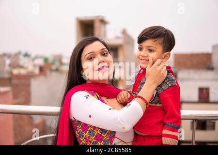 Belle, heureuse indienne jeune mère tirant les joues son petit fils coupé. Elle est debout près de la rampe et passe du temps libre avec son fils. Banque D'Images
