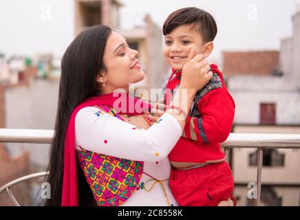 Belle, heureuse indienne jeune mère tirant les joues son petit fils coupé. Elle est debout près de la rampe et passe du temps libre avec son fils. Banque D'Images