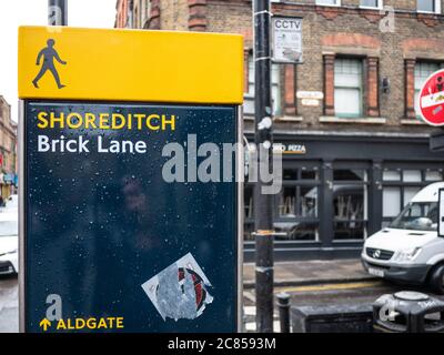 Un panneau de signalisation sur une rue animée de Londres indique aux piétons qu'ils sont à Shoreditch, sur Brick Lane. Banque D'Images