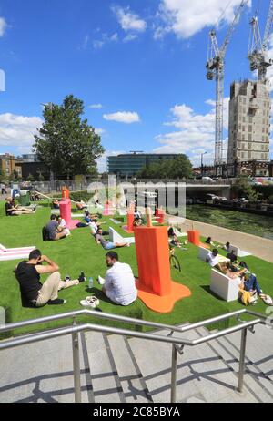 Tandis que le verrouillage Covid facilite l'herbe artificielle est remis sur les marches de Granary Square, avec des séparateurs pop à l'envelly funky pour aider à distancer les sociaux, à Kings Cross, au nord de Londres, Royaume-Uni Banque D'Images